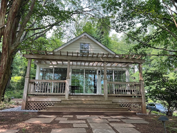 A wooden gazebo with a covered porch, large windows, and a small door.