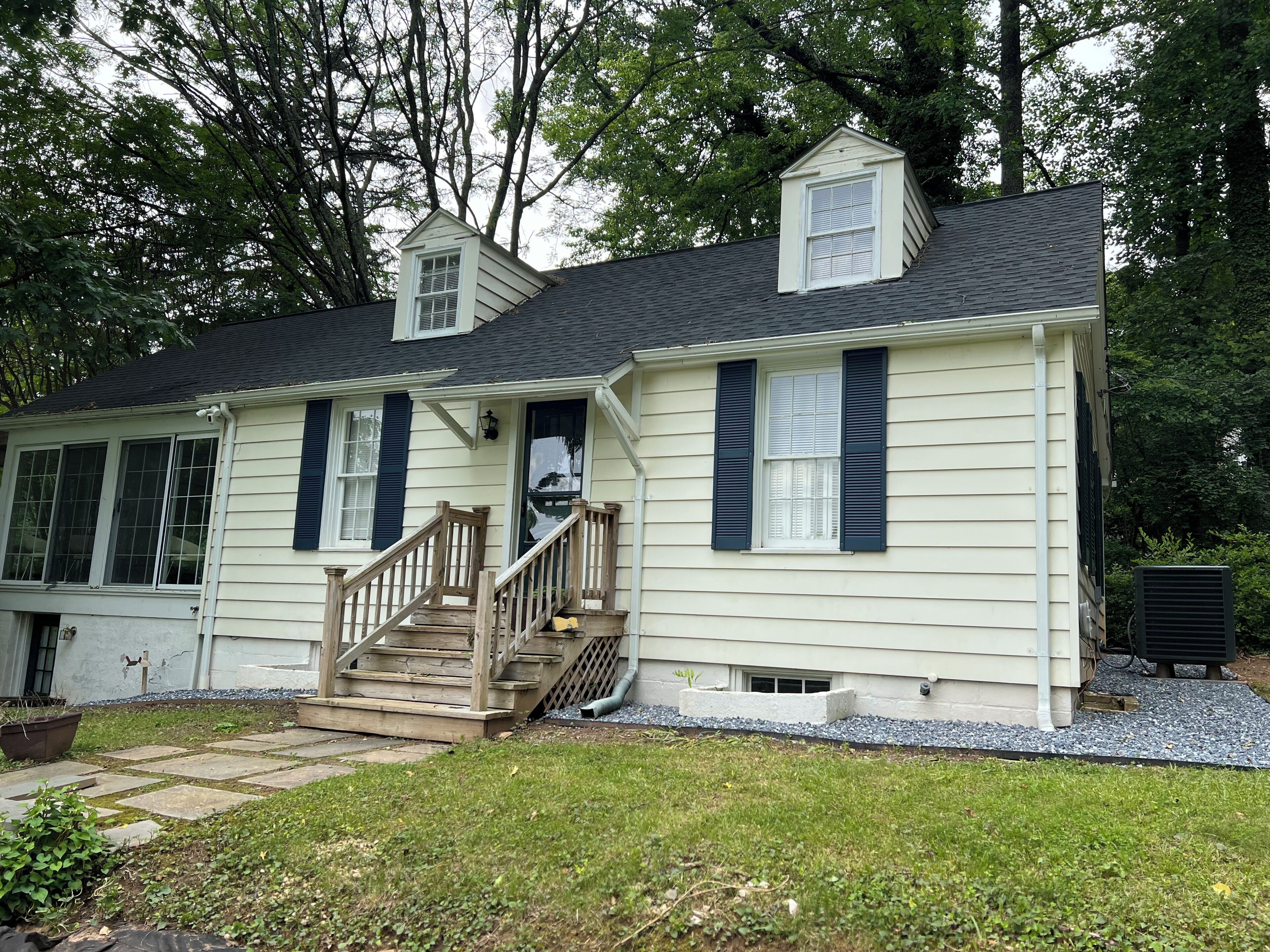 A two-story house with a front porch, a small staircase, and a chimney.