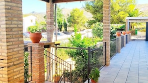 A covered outdoor area with tiled flooring, brick pillars, and metal railings.