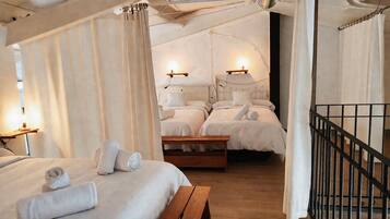 A room with two beds, a wooden bench, and a wall-mounted light fixture.