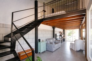 Un intérieur moderne avec un escalier en colimaçon noir, un canapé gris, un meuble bleu clair et un plafond en bois.