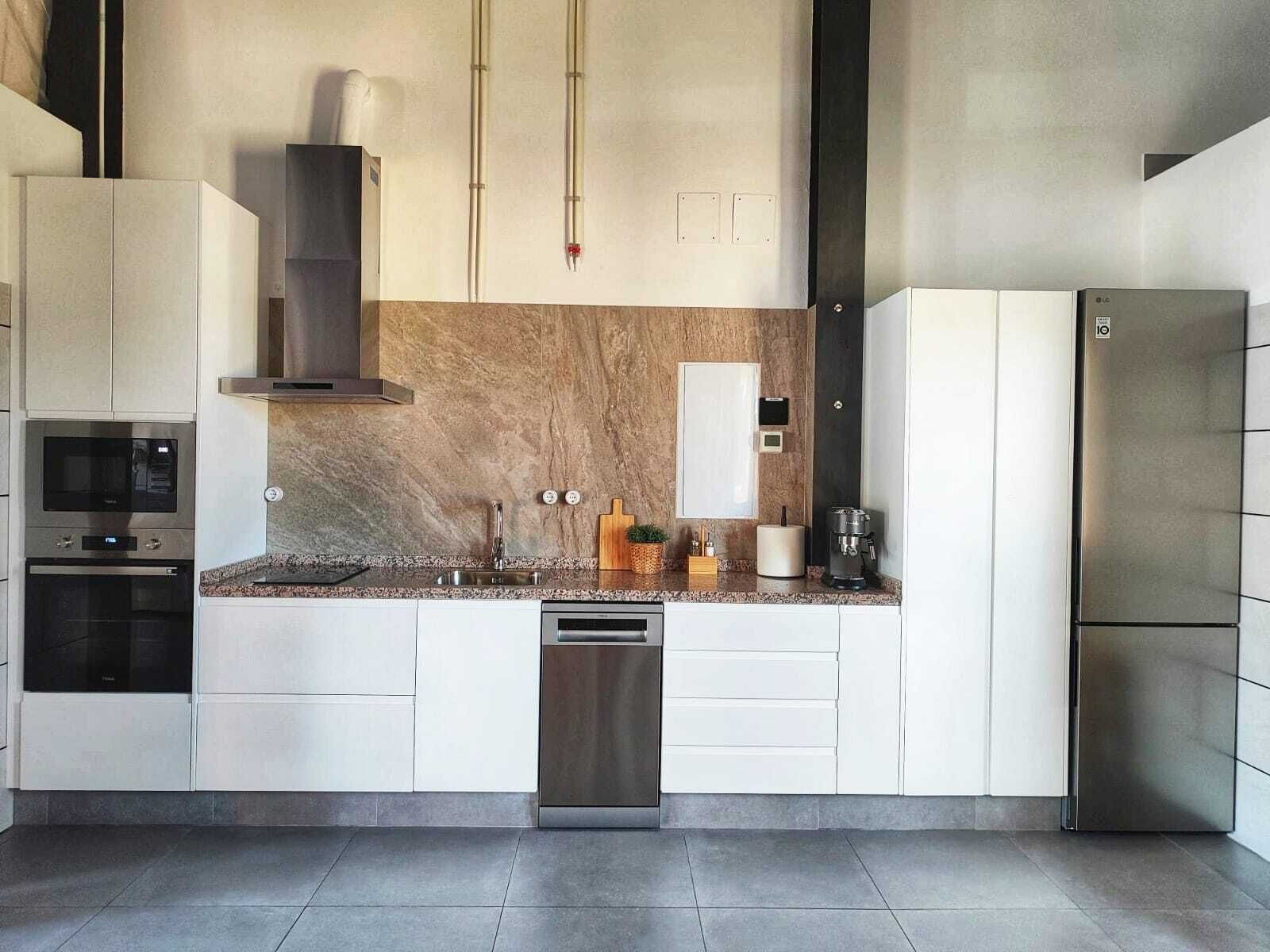 Una cocina moderna con electrodomésticos integrados, lavavajillas y refrigerador.