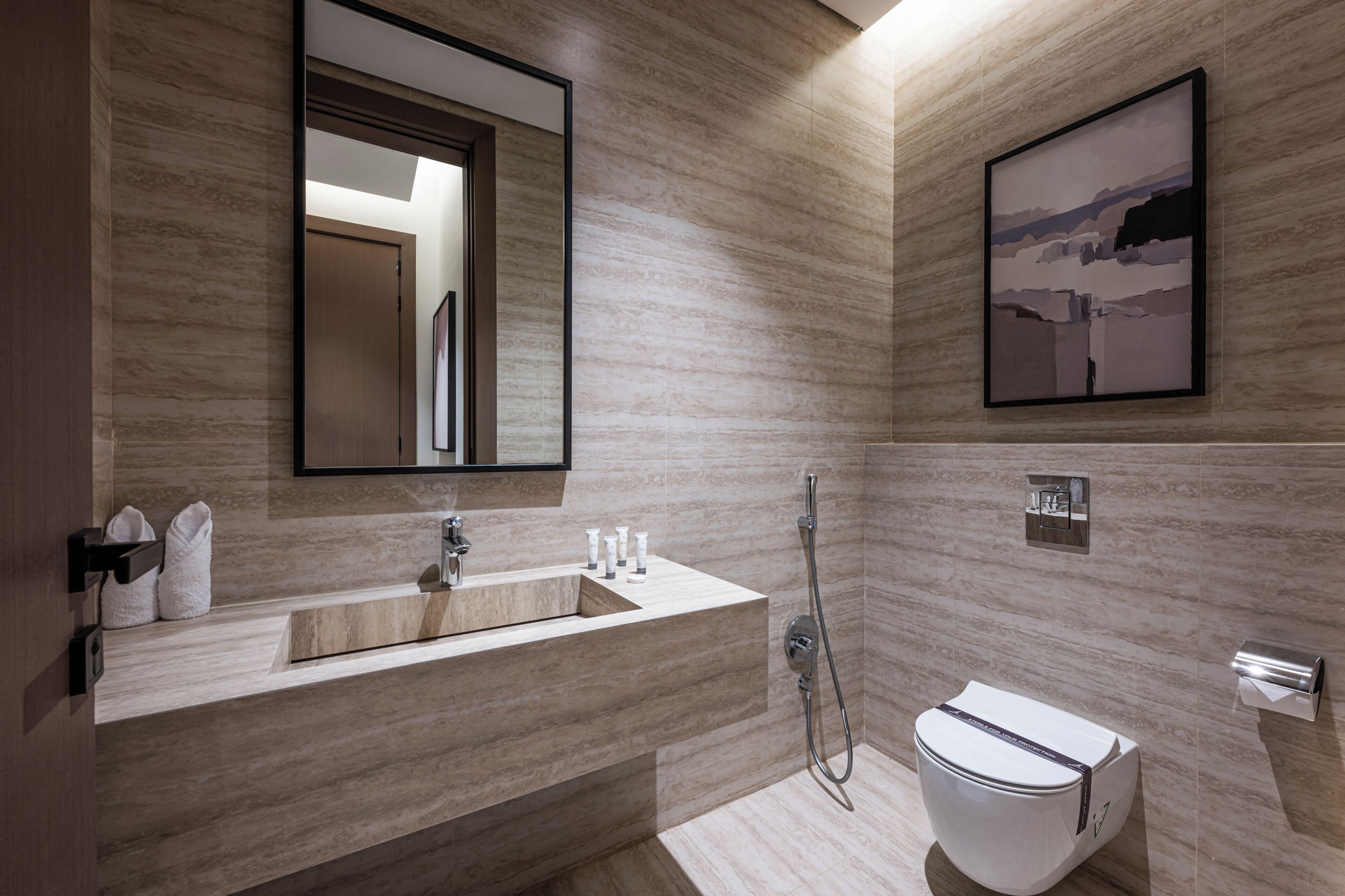 A modern bathroom with a large mirror, a sink, and a toilet.