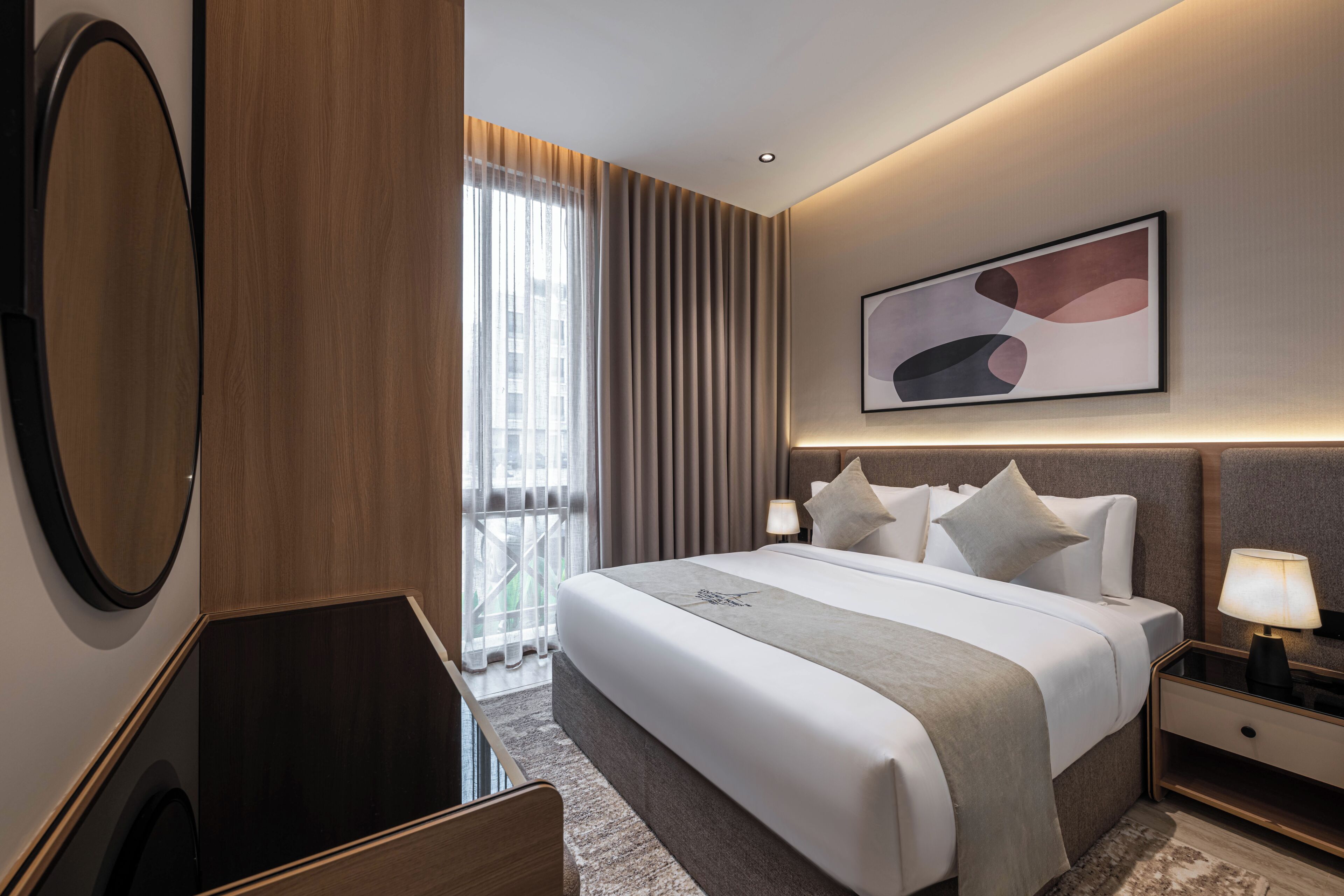 Habitación de hotel con una cama grande, mesitas de noche, un espejo y vistas al exterior.