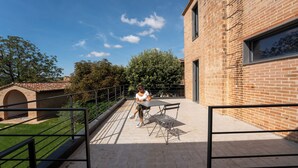 A patio area with a table and chairs, a brick building, and a clear blue sky. - Beautiful renovated farmhouse in the relaxing Umbrian countryside (Sant'Angelo di Celle)