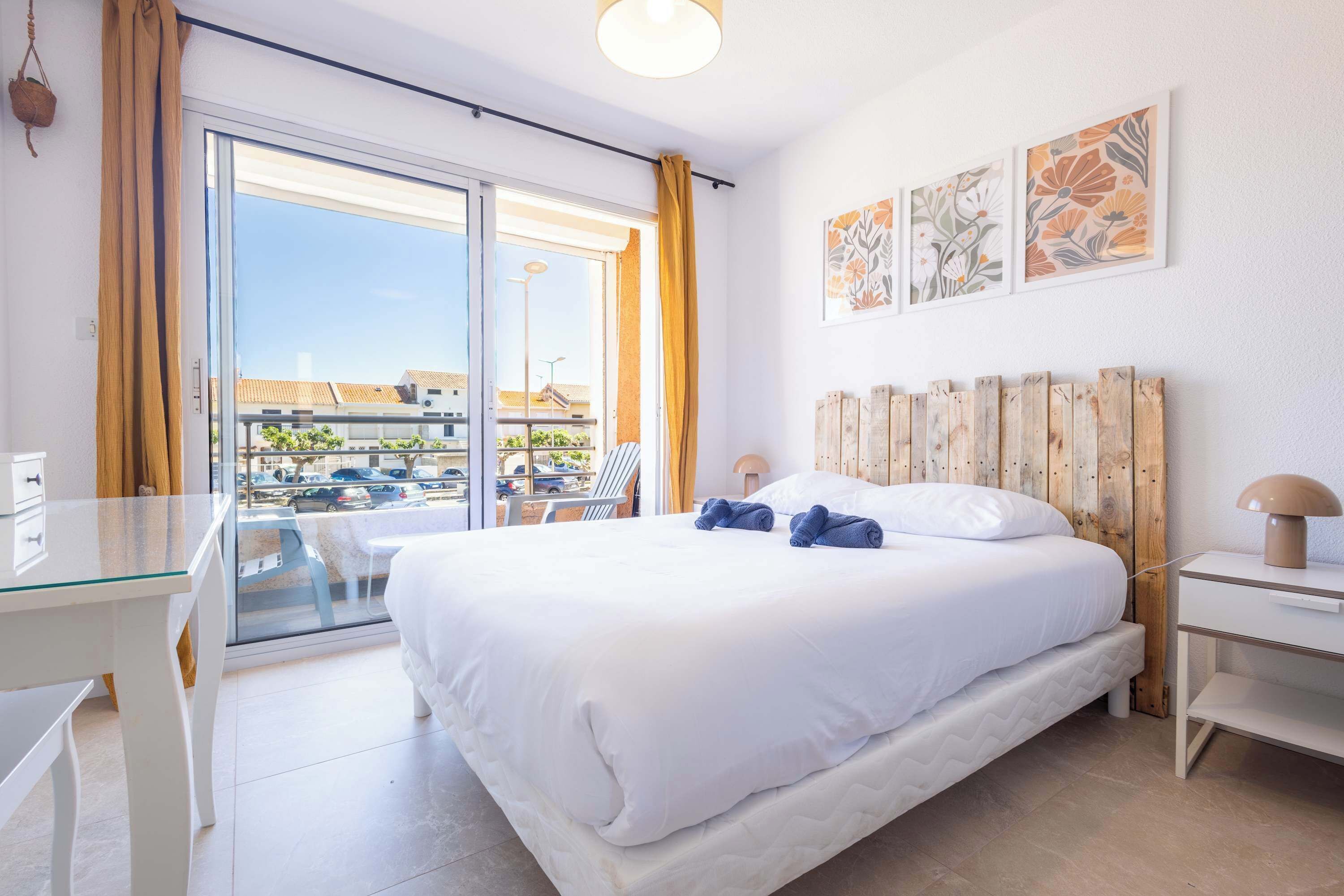 A hotel room with a bed, a desk, a chair, a window with curtains, and a view of the outside.