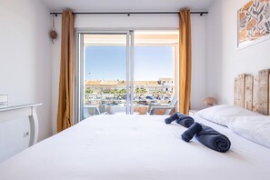 Ein Hotelzimmer mit Bett, Blick auf einen Parkplatz und einem Balkon.