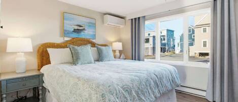 Une chambre à coucher avec un grand lit, deux tables de chevet, une fenêtre avec des rideaux et un tableau au mur.