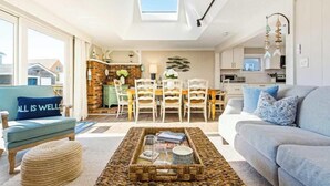 A modern living room with a sofa, ottoman, coffee table, and a dining area with chairs and a table.