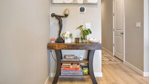 Un pasillo con una consola de madera que exhibe libros, una lámpara decorativa y un letrero en la pared que dice 'LOVE'.
