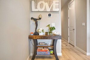 Un pasillo con una consola de madera que exhibe libros, una lámpara decorativa y un letrero en la pared que dice 'LOVE'.