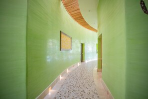Un couloir aux murs verts, doté d’un sol à motifs et d’un plafond en bois.