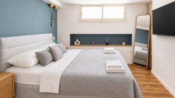 Een moderne slaapkamer met een groot bed, nachtkastjes, een raam, een spiegel en een plafondlamp.