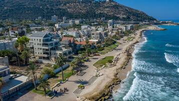 A coastal cityscape with modern buildings, a beach, and rocky coastline.