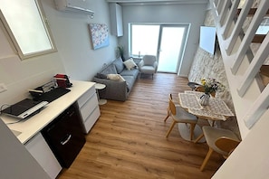 A compact living space with a kitchenette, a dining area, and a sofa. - לופט אורבני ליד המושבה הגרמנת (Haifa)