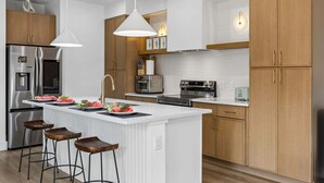 A modern kitchen with a central island, stainless steel appliances, wooden cabinets, and pendant lighting. - Cozy East Dallas Escape Minutes to Deep Ellum (Dallas)