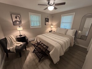 A bedroom with a bed, two bedside tables, a chair, a ceiling fan, and two windows with blinds. -  NOW BOOKING 2027, start mid May. Upscale Home, 2 Blks to Chain Boat Landing! (Waupaca)