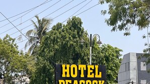A sign for Hotel Peacock Rooms with a directional arrow. - Hotel Peacock  (Anand)