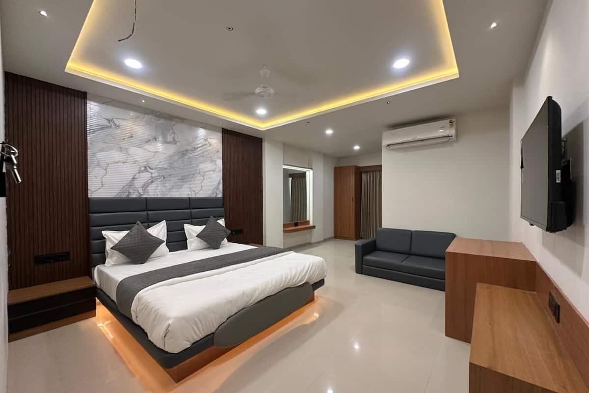 A modern bedroom with a bed, a sofa, an air conditioning unit, and a television.