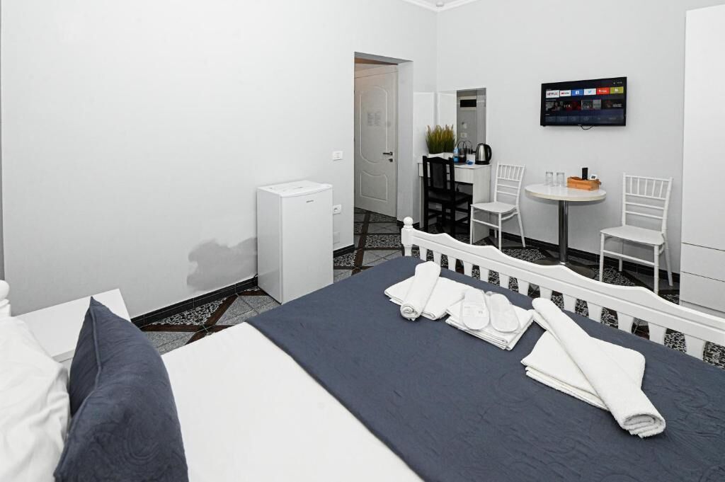 Habitación de hotel con cama, escritorio, silla, televisor y refrigerador pequeño.