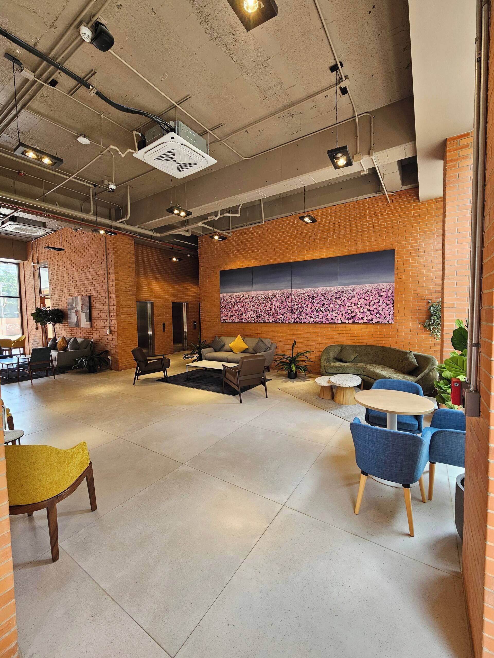 A spacious lounge area with brick walls, a large abstract painting, and modern furniture.