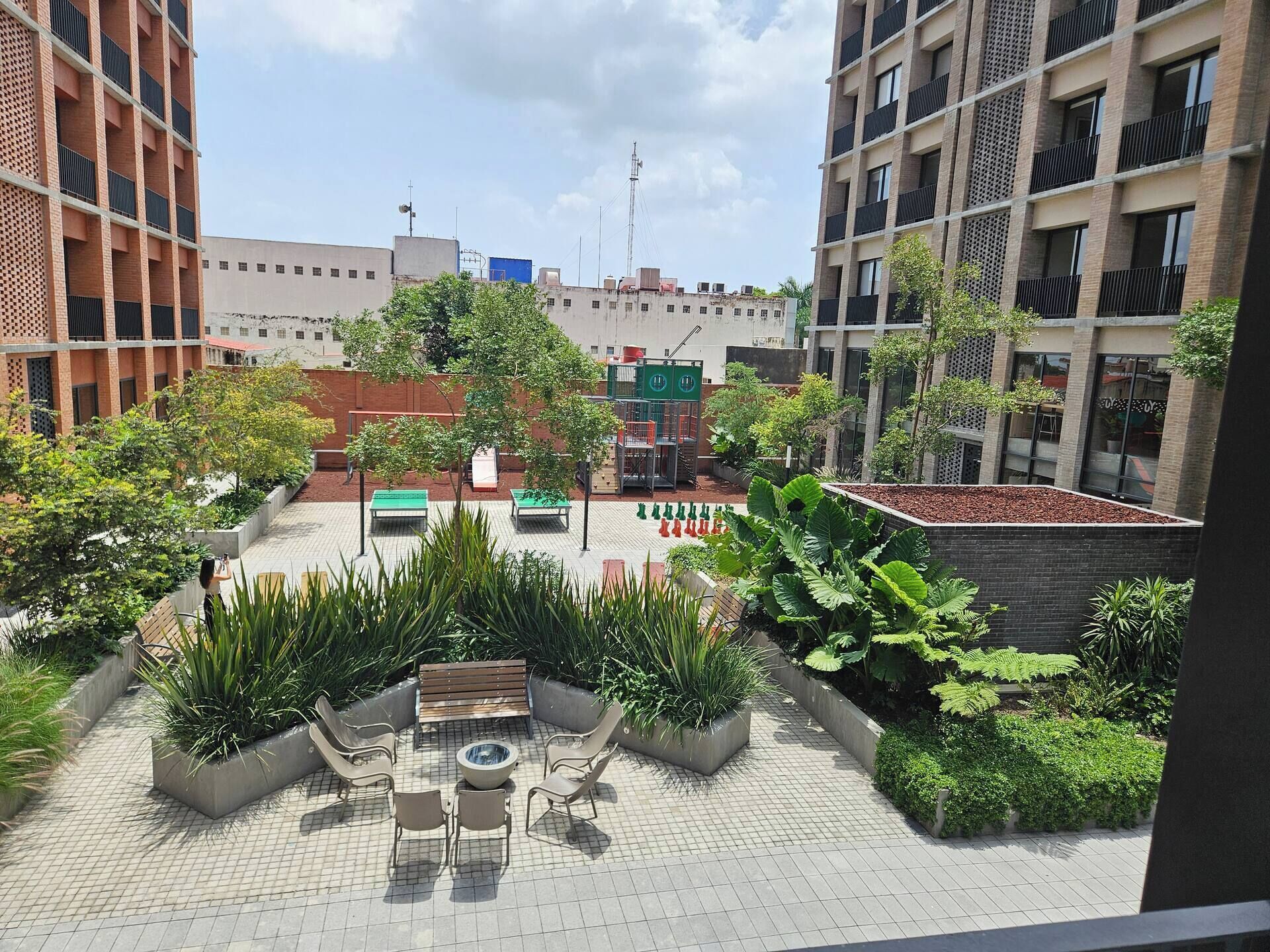 A rooftop garden with seating, planters, and a view of surrounding buildings.