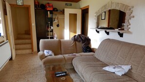 A living room with a sofa, a coffee table, and a fireplace. There is a staircase leading to another room. - Old sheepfold surrounded by fields and mountains (La Chapelle-en-Vercors)