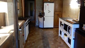 A kitchen with wooden cabinets, a refrigerator, and a wooden floor. - Old sheepfold surrounded by fields and mountains (La Chapelle-en-Vercors)