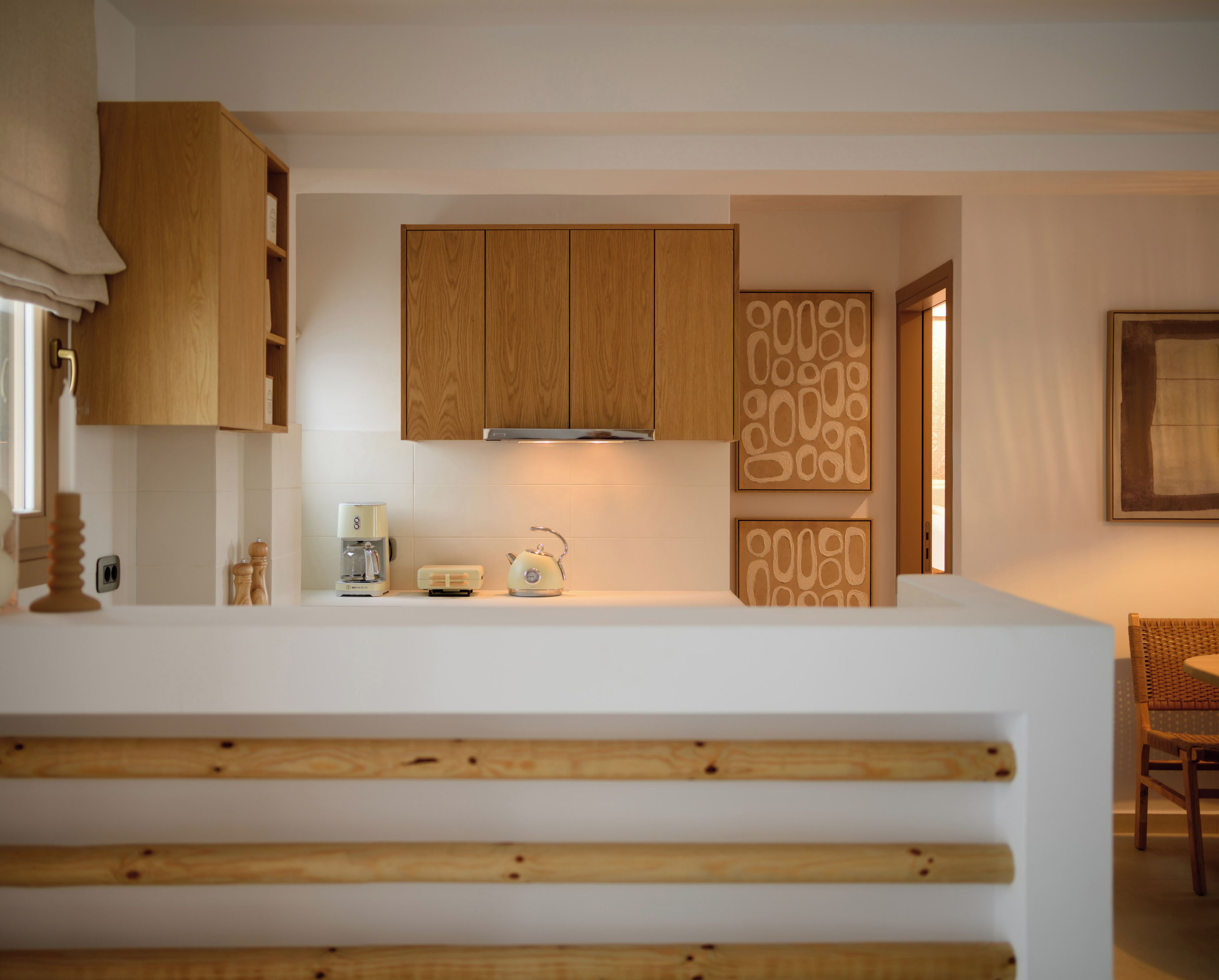 A modern kitchen with wooden cabinets, a coffee machine, and a kettle on the counter.