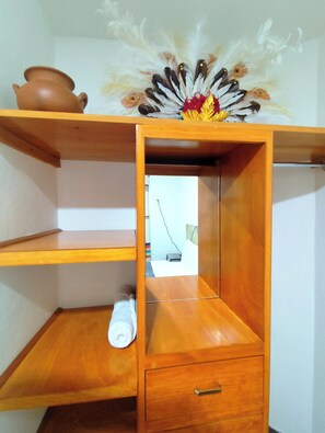 Een houten plank met een decoratief object, een klein wit voorwerp en een spiegel die een kamer weerspiegelt.