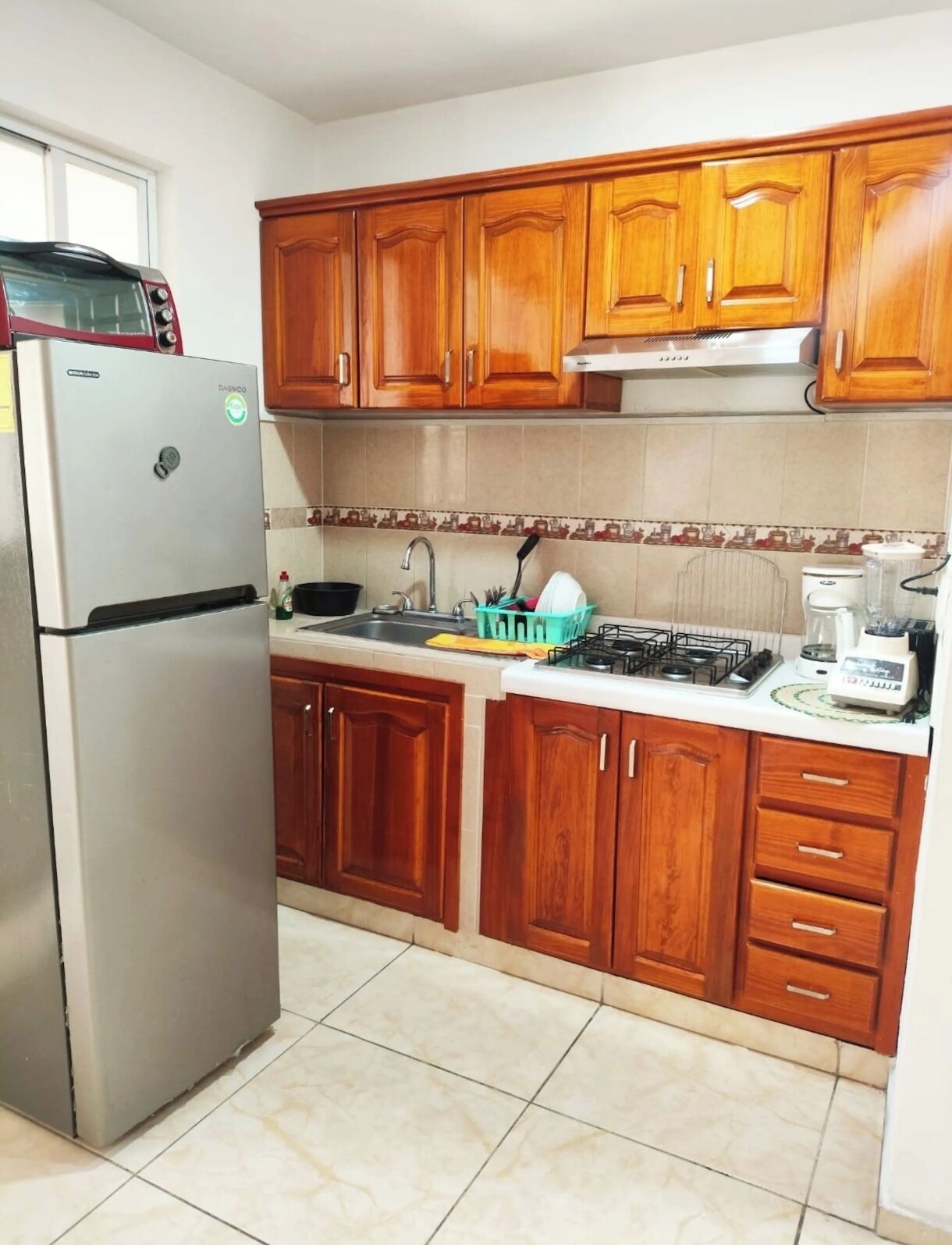 A kitchen with wooden cabinets, a stainless steel refrigerator, a gas stove, and a coffee maker.