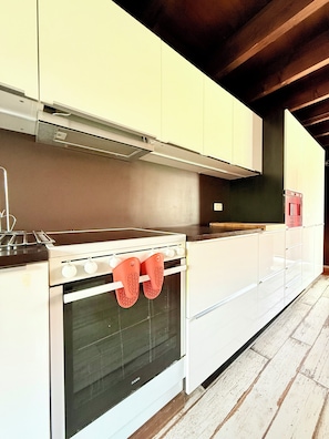 A kitchen with white cabinets, a stove, and an oven. - Family duplex with terrace in Nieuwpoort (Nieuwpoort)