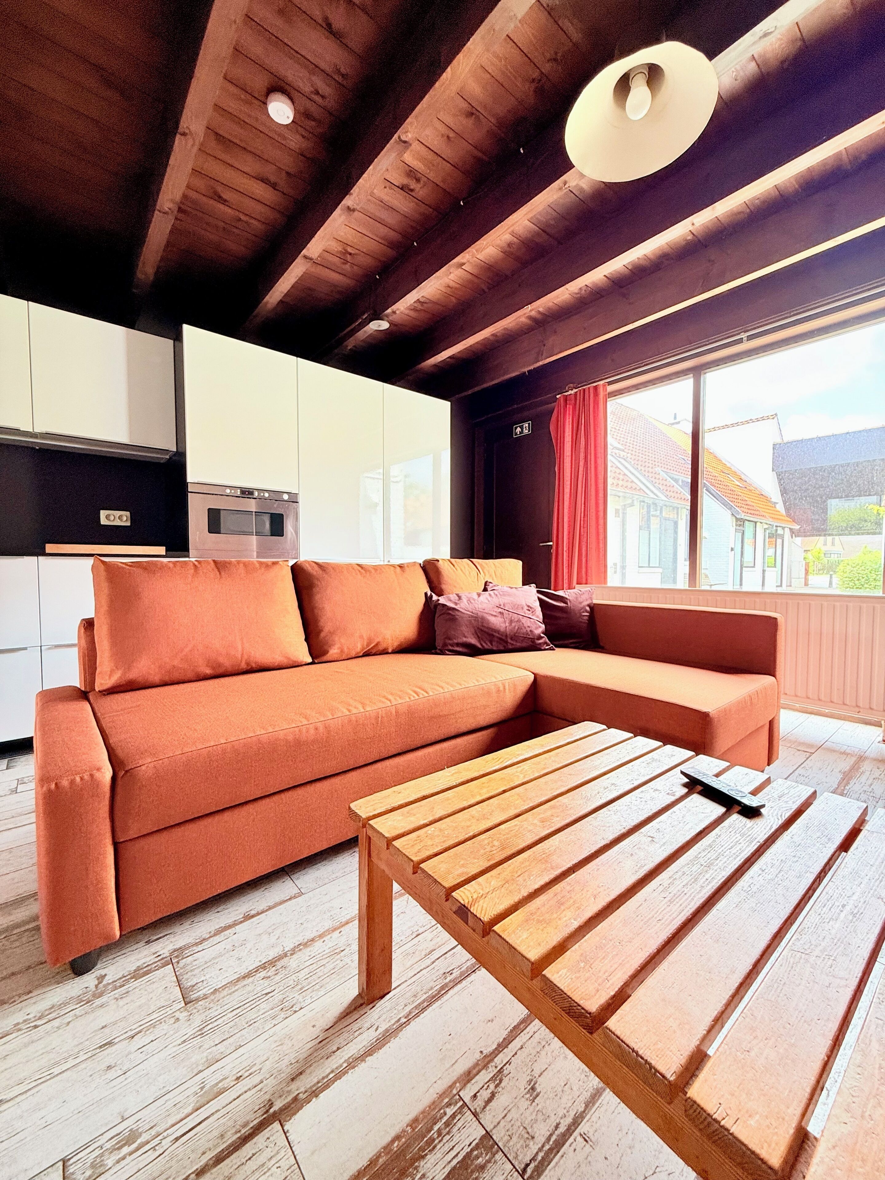 Ein modernes Interieur mit Holzboden, einer Couch, einem Couchtisch aus Holz und einer Küchenzeile.