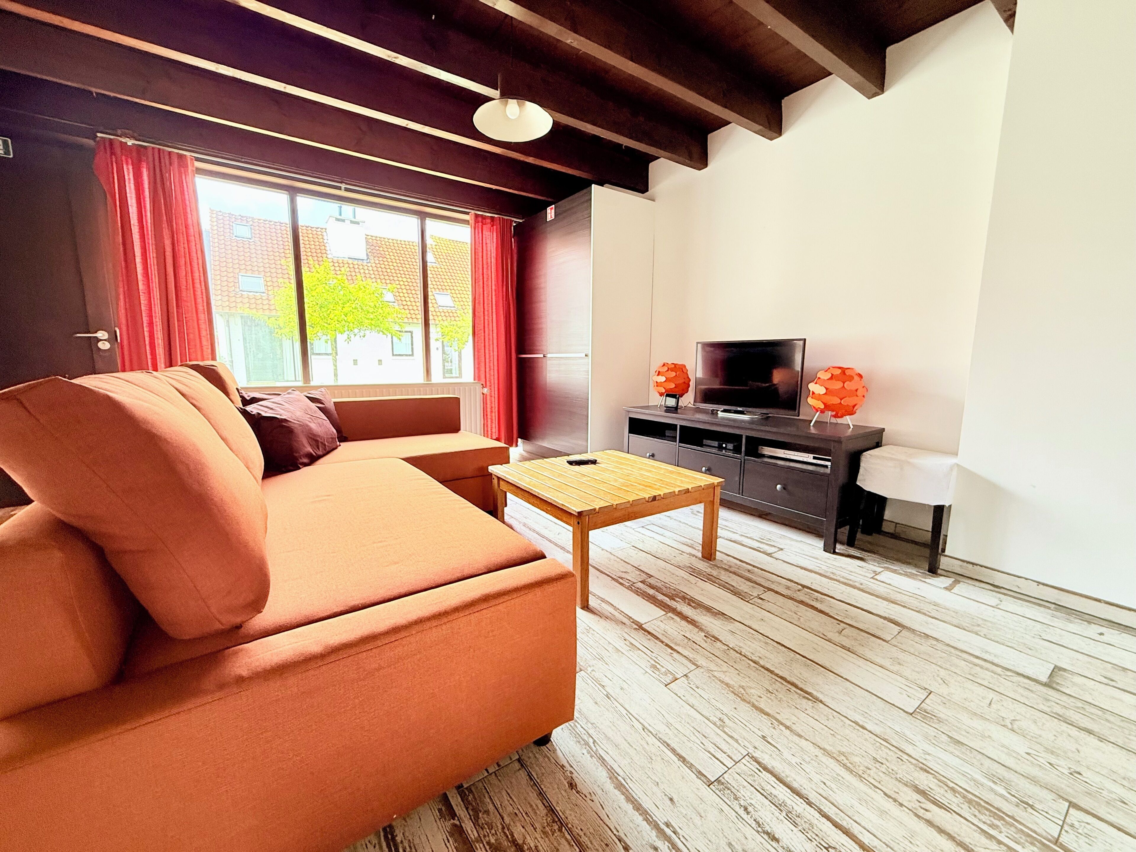 A living room with a sofa, a small table, a TV, and a cabinet.