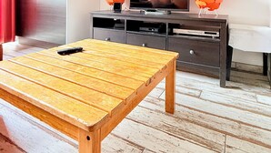Ett rum med ett träbord, en tv på ett mörkt skåp och två orange, sfäriska föremål på skåpet.