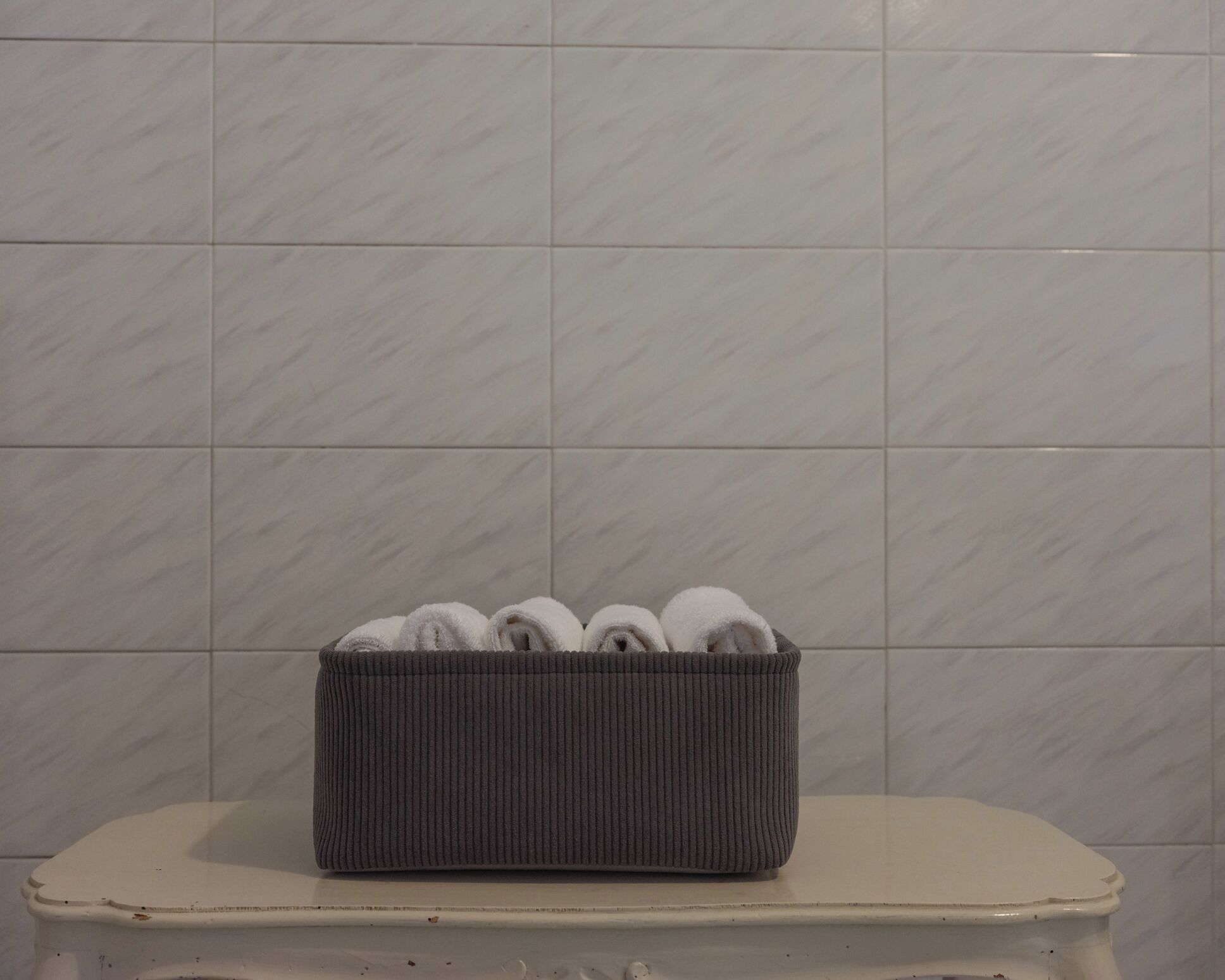Un baño con un inodoro blanco y un cesto para toallas gris al lado.