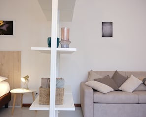 A modern living room with a sofa, a coffee table, a lamp, and shelves with decorative items. - Dimora Giardino di Giulietta (Verona)