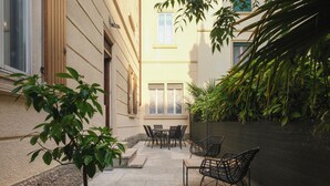 A patio with a table and chairs, a potted plant, and a wall with climbing plants. - Dimora Giardino di Giulietta (Verona)