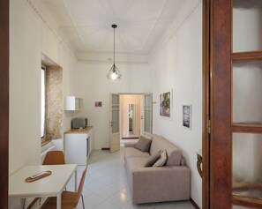 A spacious living area with a sofa, a dining table, and a kitchen area. - Dimora Giardino di Giulietta (Verona)