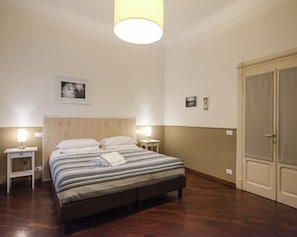 A bedroom with a bed, bedside lamps, a wooden headboard, a door, and a wall-mounted picture. - Dimora Giardino di Giulietta (Verona)