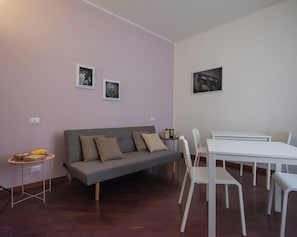 A living room with a grey sofa, white chairs, a white table, and two framed pictures on the wall. - Dimora Giardino di Giulietta (Verona)