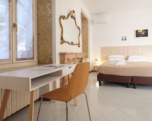 Habitació d'hotel amb escriptori, cadira, llit i un mirall decoratiu.