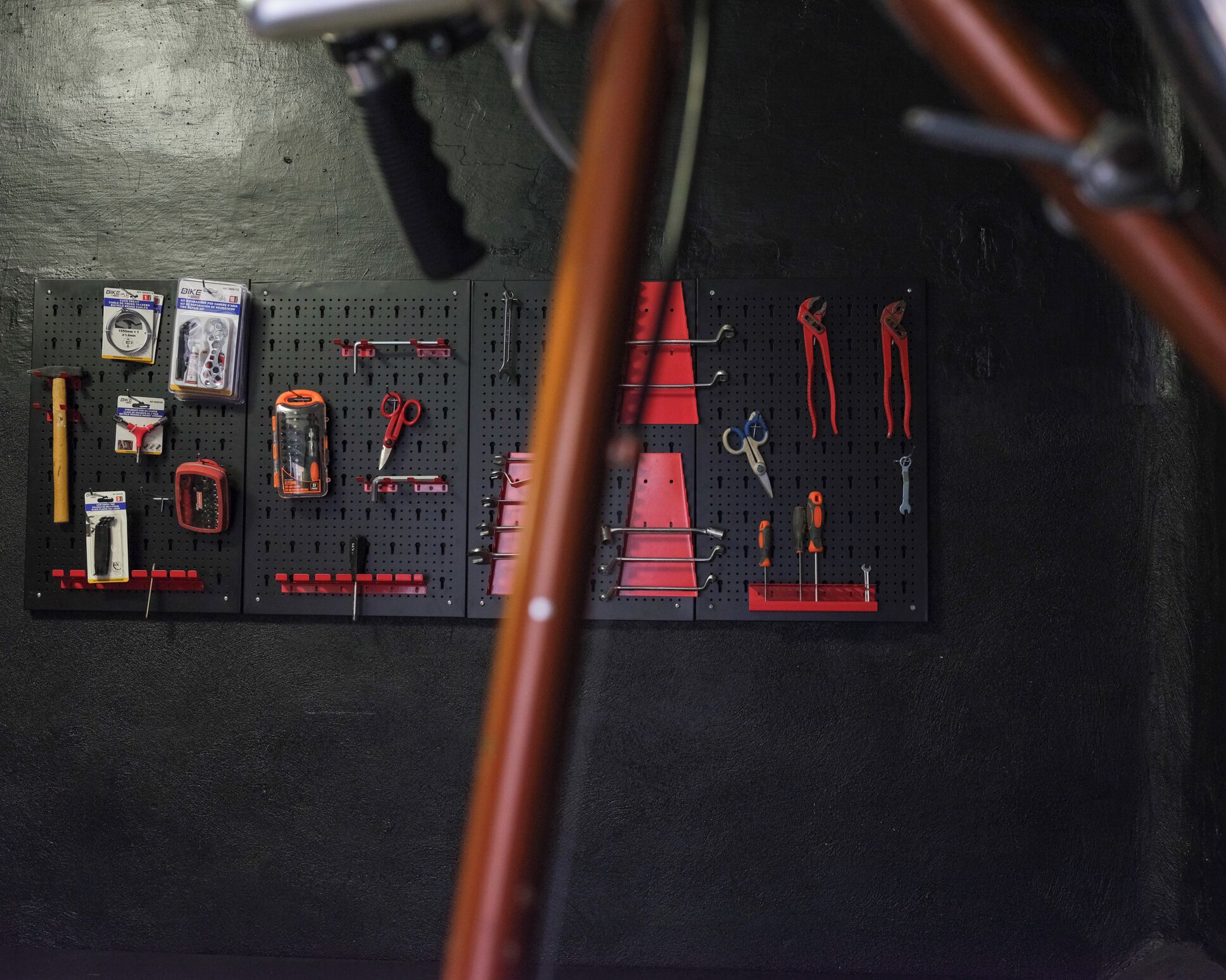 A pegboard with tools and bike parts.