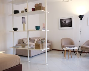 A modern living room with a sofa, a coffee table, a floor lamp, and a bookshelf. - Dimora Giardino di Giulietta (Verona)