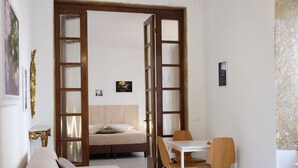 A room with a bed, a sofa, a dining table with chairs, and a door leading to another room. - Dimora Giardino di Giulietta (Verona)