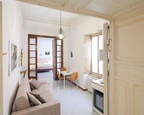 A room with a sofa, a dining table, a bed, and a fireplace.