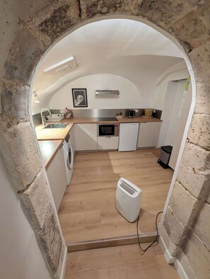Eine kleine Küche mit Waschmaschine, Mikrowelle und einem kleinen Kühlschrank.