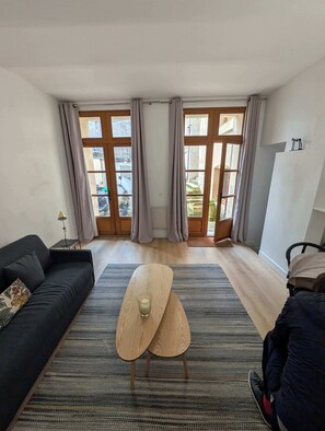 Ein modernes Wohnzimmer mit einer Couch, einem Couchtisch und Blick durch große Fenster.