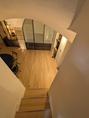 Ein modernes Interieur mit Treppe, Holzboden und Küchenbereich, der durch eine Wand aus Stein akzentuiert wird.
