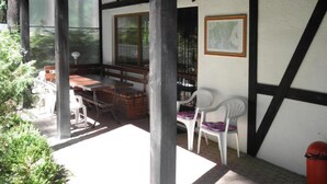 Un espacio de estar techado al aire libre con una mesa y sillas de madera, un mapa en la pared y vistas a zonas verdes.